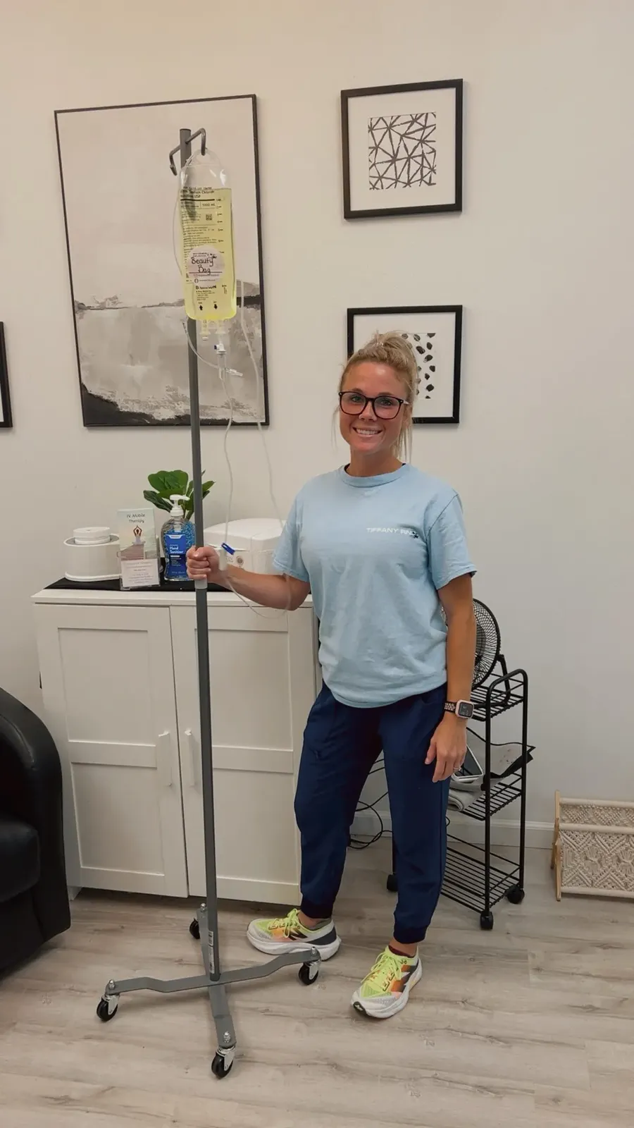 Tiffany, a registered nurse, beside an IV pole with a vitamin bag